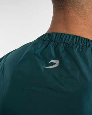 Man in a green sauna suit tracksuit with a white boxraw logo on the chest as well as adjustable wrist straps and made from polyester.