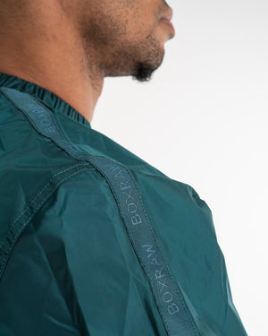 Man in a green sauna suit tracksuit with a white boxraw logo on the chest as well as adjustable wrist straps and made from polyester.
