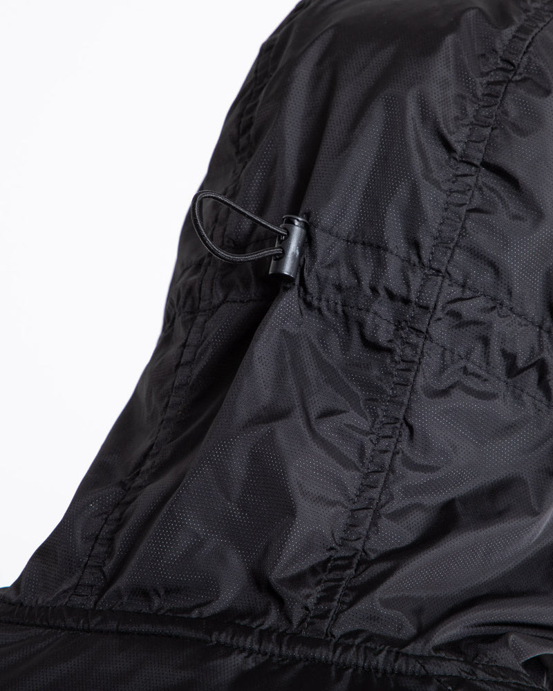 Man in black zipped windbreaker with hood and reflective big boxraw strike logo across left body panel made from nylon.
