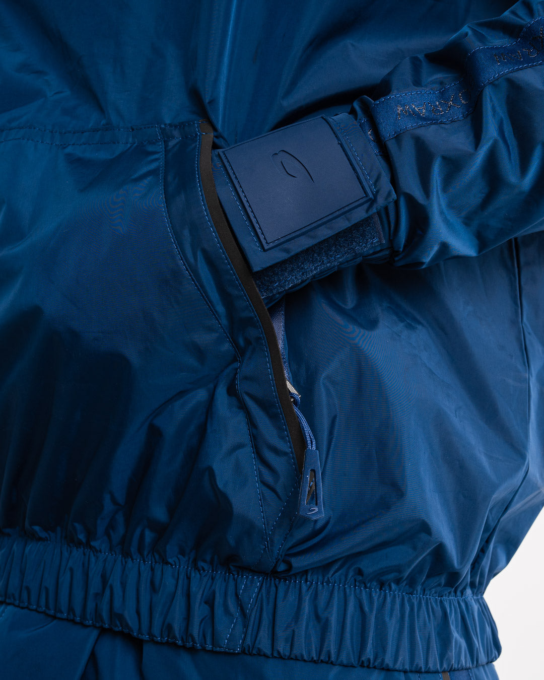 Man in a navy sauna suit tracksuit with a white boxraw logo on the chest as well as adjustable wrist straps and made from polyester.