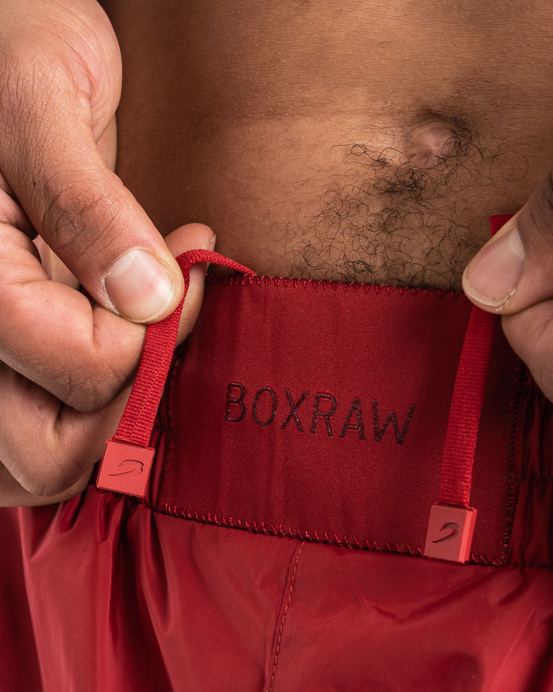 Man in a red sauna suit tracksuit with a white boxraw logo on the chest as well as adjustable wrist straps and made from polyester.