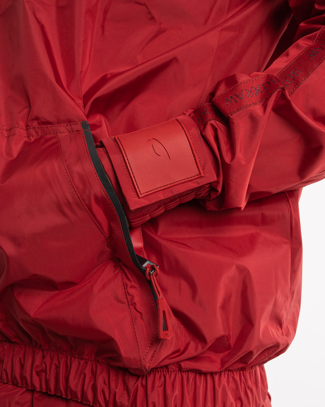 Man in a red sauna suit tracksuit with a white boxraw logo on the chest as well as adjustable wrist straps and made from polyester.