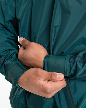 Man in a green sauna suit tracksuit with a white boxraw logo on the chest as well as adjustable wrist straps and made from polyester.