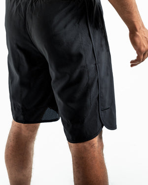 Man in black training shorts with adjustable waistband and side zipped pockets as well as an embroidered white boxraw strike logo.