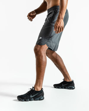 Man in charcoal training shorts with adjustable waistband and side zipped pockets as well as an embroidered white boxraw strike logo.