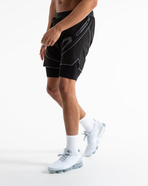 Man in black shorts with compression shorts underlayer with reflective detailing and side zipped pockets