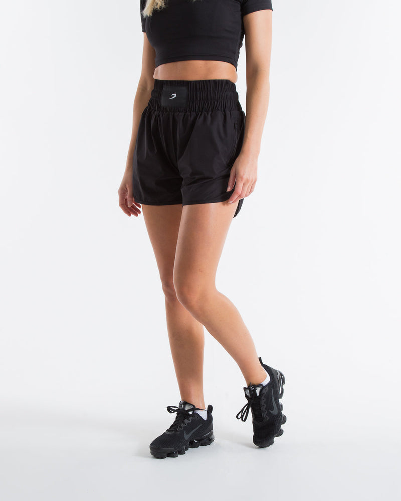 Women in black high waisted shorts with woven strike logo waistband patch
